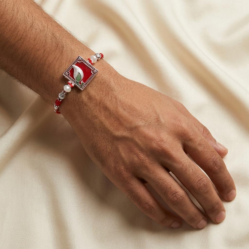 Traditional Silver Peacock Feather Rakhi with Red & Pearl Beads