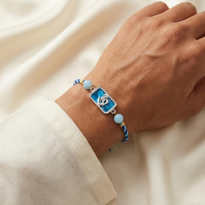 Silver Om Ganesh Motif Rakhi with Blue Braided Thread