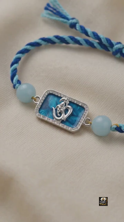 Silver Om Ganesh Motif Rakhi with Blue Braided Thread